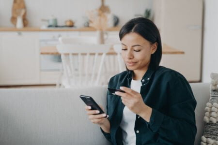 Home Affairs Online ID Application smiling female holding bank credit card smartphone